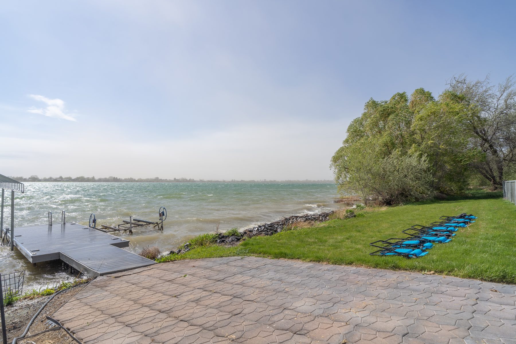 Dock, lifts and riprap shore on a windy afternoon, kayaks on the lawn